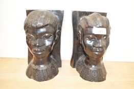 A pair of African carved hardwood bust-form bookends, each measuring 21cm high