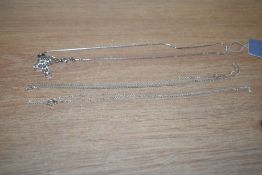 A small collection of silver and white metal necklaces, comprising a silver curb link neck chain,