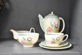 An early 20th century Susie Cooper part tea service, hand coloured in foliage on a cream ground,