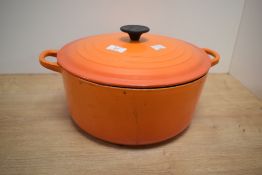 A large cast iron Le Creuset casserole dish with lid in volcanic orange colour, w30cm.