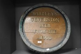 An oak beer barrel lid with green rim, salvaged and repurposed to use as an adverting sign,