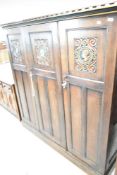A late 19th or early 20th Century oak triple wardrobe having pictorial heads to panelled doors