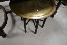 An Eastern brass tray table with folding turned stand, diameter approx. 60cm