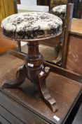 A 19th century mahogany piano stool having circular adjustable seat with moquette style upholstery