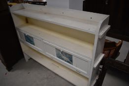 A vintage painted shallow bookshelf with flapped storage sections to centre shelf, width approx.