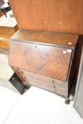 An early 20th Century walnut bureau having three drawers and shaped legs with ball and claw feet,