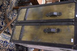 A reproduction steamer trunk on folding stand