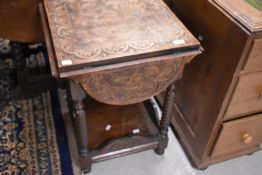 A carved oak occasional table having drop flaps and undertier