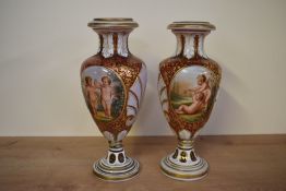 An attractive pair of Bohemian cranberry glass and enamelled bulbous vases, decorated having