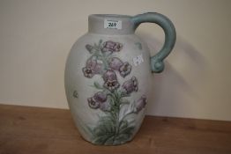 A large early 20th century Danesby ware ceramic jug, decorated having blue bell reliefs on an