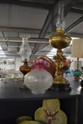 An early 20th century brass oil lamp with cherub decoration, supported on a black marble base,