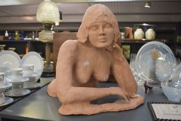 An attractive terracotta sculpture of a nude female figure, crouching with