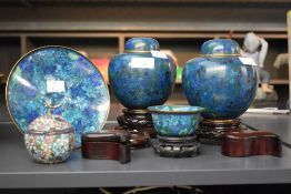 A pair of dark blue Cloisonné enamel ginger jars, supported on wooden plinths, h15.5, sold