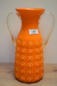 A large mid-century tangerine glass vase, having short neck with clear handles and textured pattern,