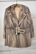 A well preserved mink fur coat, having a wide notched lapels and featuring a belt with gold