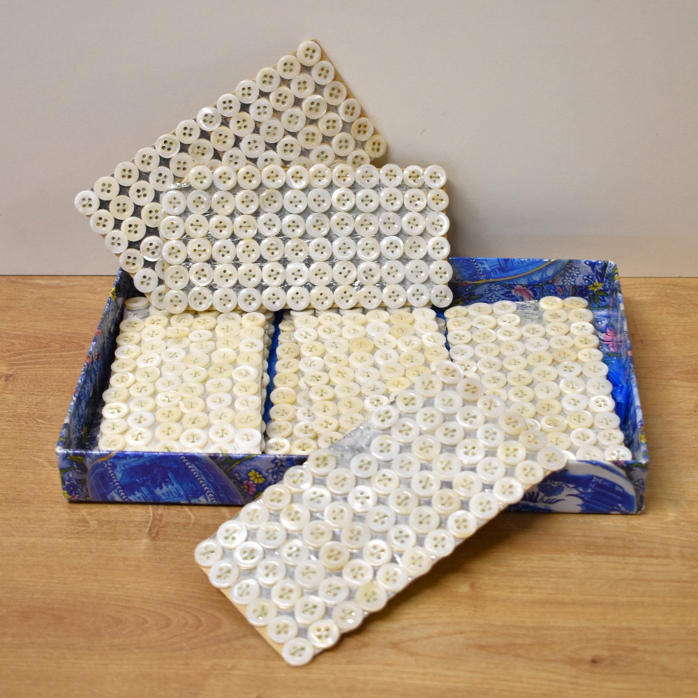 A quantity of vintage freshwater-shell shirt buttons, held in place on silver card with green
