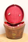 An antique top hat carrying case in brown leather, has significant visible aging and the handle is