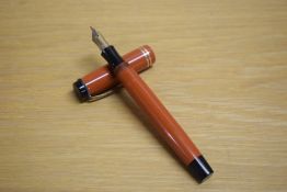 A Parker Duofold Senior button fill fountain pen in orange with two gold bands to the cap having 14K