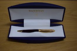 A boxed Waterman Edson ballpoint pen in ruby red with gold cap. Booklet and refill in box. Slight
