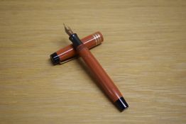 A Parker Duofold Junior button fill fountain pen in orange with three gold bands to the cap having