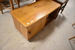 A light Ercol TV unit having sliding doors and castors, width approx. 89cm