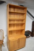 A light Ercol bookcase having double cupboard under, approx dimensions H214cm W91cm D44cm
