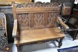 A heavily carved oak settle having turned turned legs and H stretcher, width approx. 117cm
