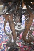 A dark stained occasional table in the Eastern style with heavily carved top and supports , diameter