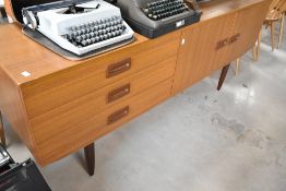 A vintage teak effect sideboard having stylised recessed handles, width approx 176cm