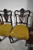 A pair of early 20th Century mahogany salon chairs having shaped foliate backs
