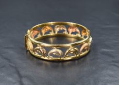 A yellow metal hinged bangle stamped 750 having moulded three colour gold brushed and polished