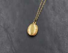 A small 9ct gold oval locket having an engraved border, with a fine 9ct gold rope chain, approx