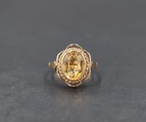 A 9ct gold citrine ring having an oval stone in a collared setting within a decorative sheped mount,