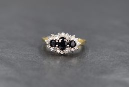 An 18ct sapphire and diamond cluster ring, the three graduated oval cut sapphires in a twenty