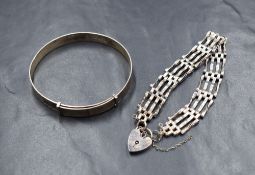A silver four bar gate bracelet, having a silver heart padlock and broken safety chain, along with a