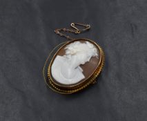 A shell cameo brooch, depicting a maiden in profile having floral decoration to hair, in a yellow