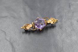A yellow metal bar brooch stamped 9ct having central hexagonal amethyst in decorative floral mount