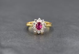 An 18ct gold ruby and diamond cluster ring having a central diamond within a surround of ten small
