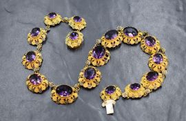 An ornate rivière costume necklace, the graduated purple paste stones in yellow metal bezel settings