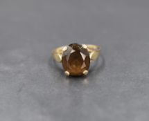 A yellow metal smokey quartz ring having a four claw set raised basket mount to shaped shoulders