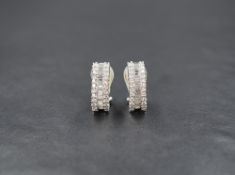 A pair of white gold hoop and post diamond earrings stamped 750 having central row of baguette cut
