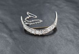 An Art Deco style white gold graduated diamond set crescent moon shaped brooch, not marked but tests