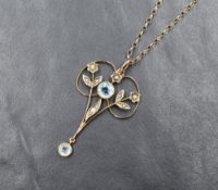 A yellow metal Edwardian pendant having aqua marine style collared stone in a floral mount with seed