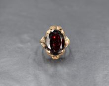 A yellow metal (presumed gold) garnet ring, the large oval cut garnet in a four claw setting in a