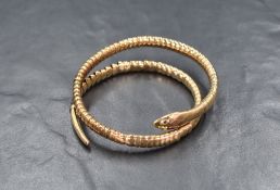 A yellow metal serpent bracelet, marked 9ct, the expandable coiled snake, having green gemstone