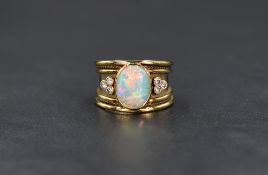 An 18ct gold Artisan style shaped band ring having a collared oval opal flanked by a trio of small