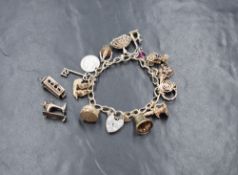 A silver curb link charm bracelet, having a heart padlock and thirteen white metal charms