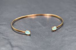 A 9ct gold tension bangle of narrow form having claw set opal terminals, approx 3.5g