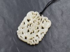 A carved jade pendant, of pierced form having a central character with decorative scroll work, on