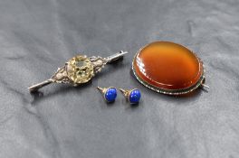 A white metal citrine brooch, the round cut citrine in a four claw setting flanked by thistles,